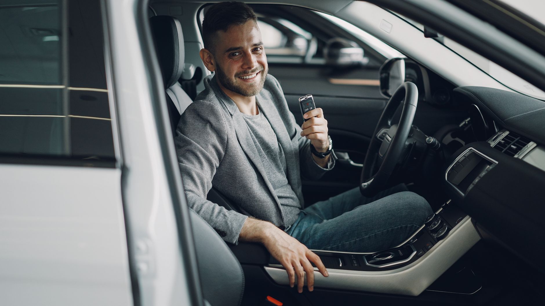 Man sitting in a car seat holding up a key fob