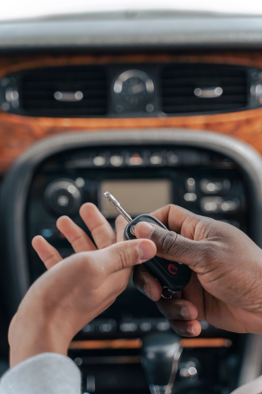 Hands exchanging a car key fob inside a vehicle