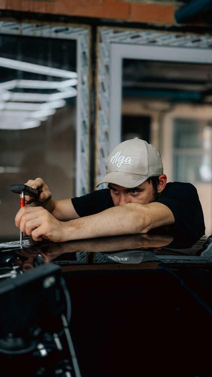 Technician leaning over a car bonnet working with a tool