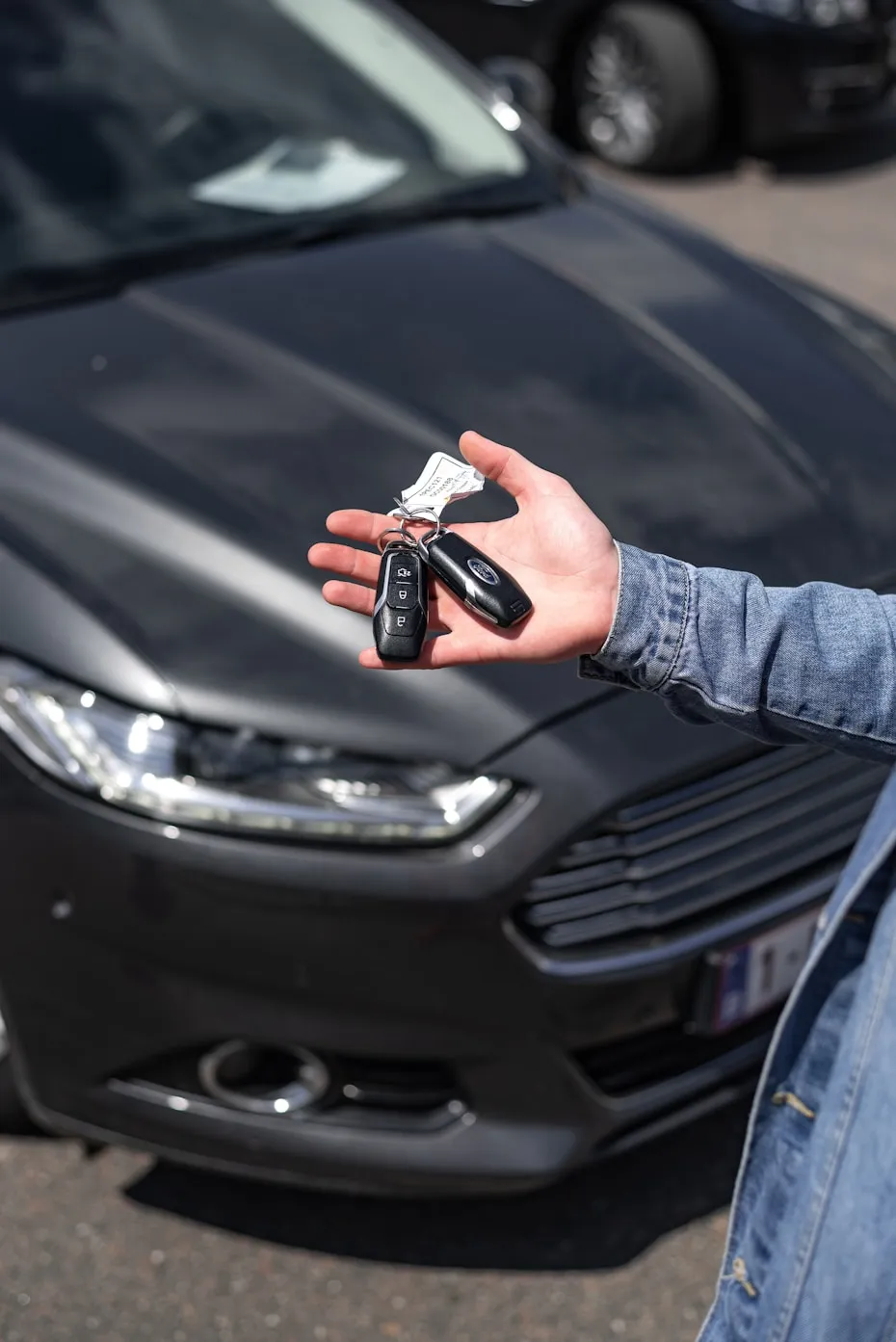 Locksmith holding a car key fob in front of a vehicle